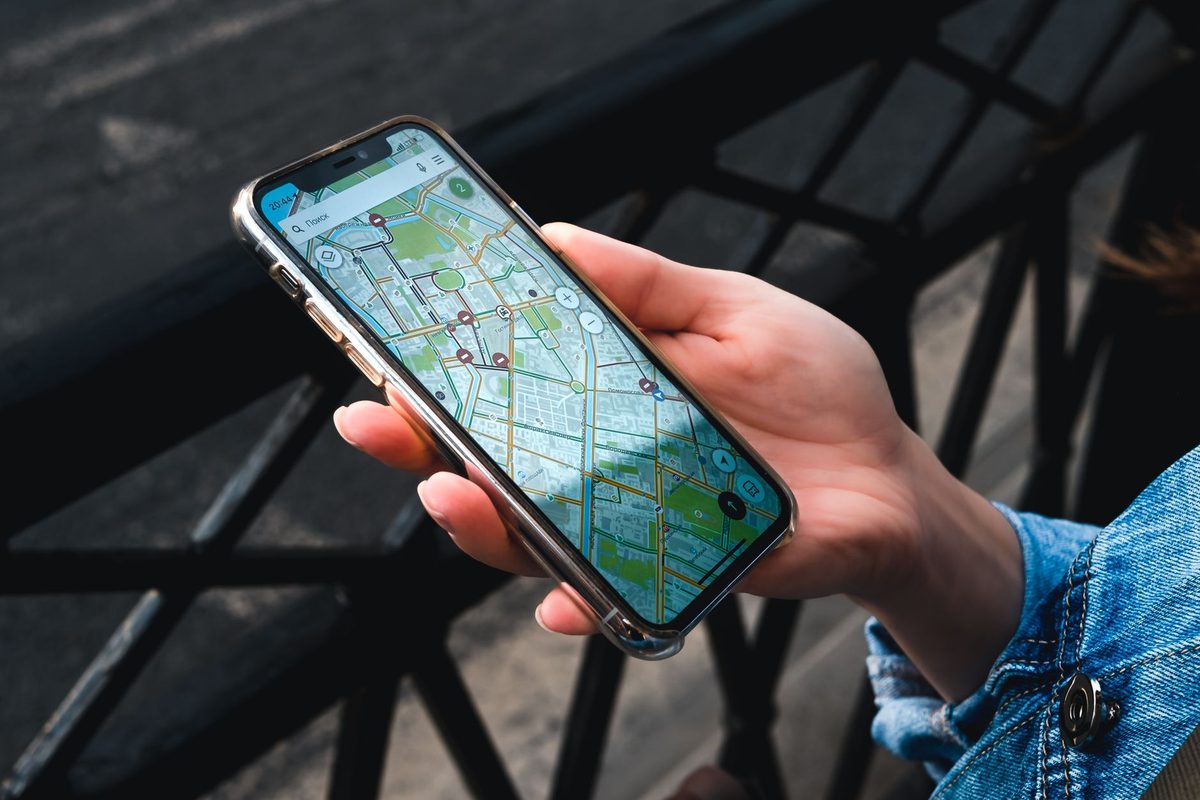 手に持ったスマートフォンに、地図アプリが表示されている様子